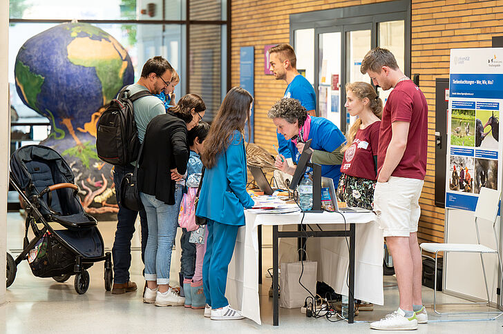 Besucher*innen informieren sich an einem Stand im UBB