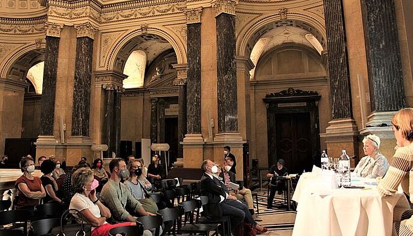 Foto von Veranstaltung "Umwelt im Gespräch". Menschen sitzen im Naturhistorischen Museum und diskutieren