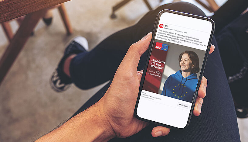 Hand hält Smartphone, auf dem eine Social Media-Wahlwerbung der deutschen SPD abgebildet ist.